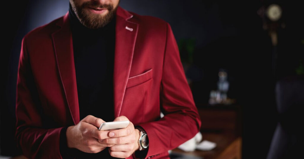 Man wearing a burgundy suit with a black shirt.