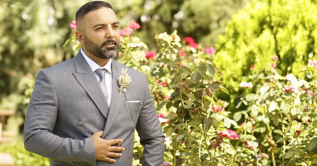 Man wearing a medium grey double-breasted suit with a boutonniere