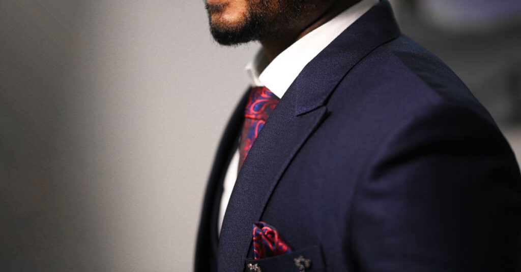 Man wearing a midnight blue suit with a patterned tie and pocket square.