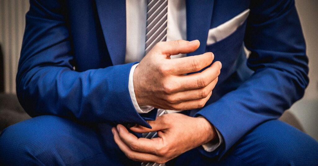Man wearing a royal blue or cobalt blue suit with a striped tie and white pocket square.