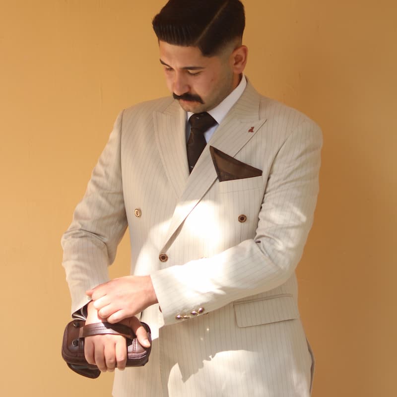Man in light suit adjusting his cuff