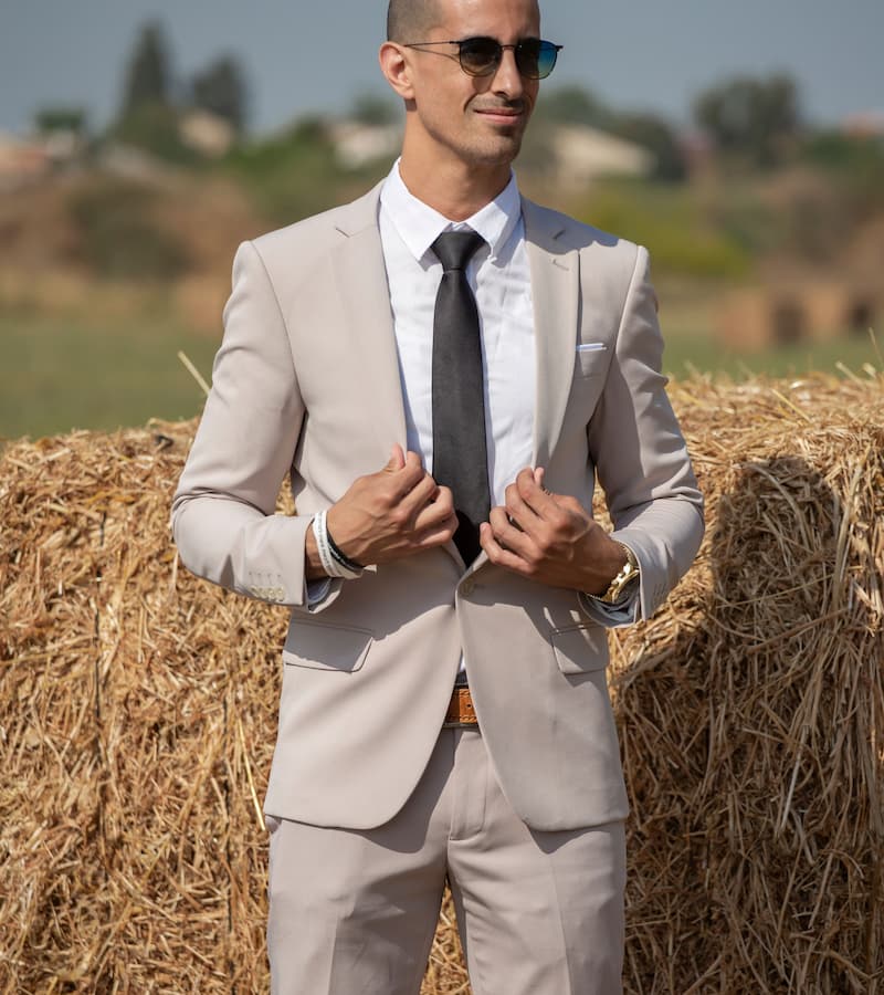 Man in a suit posing by hay bales