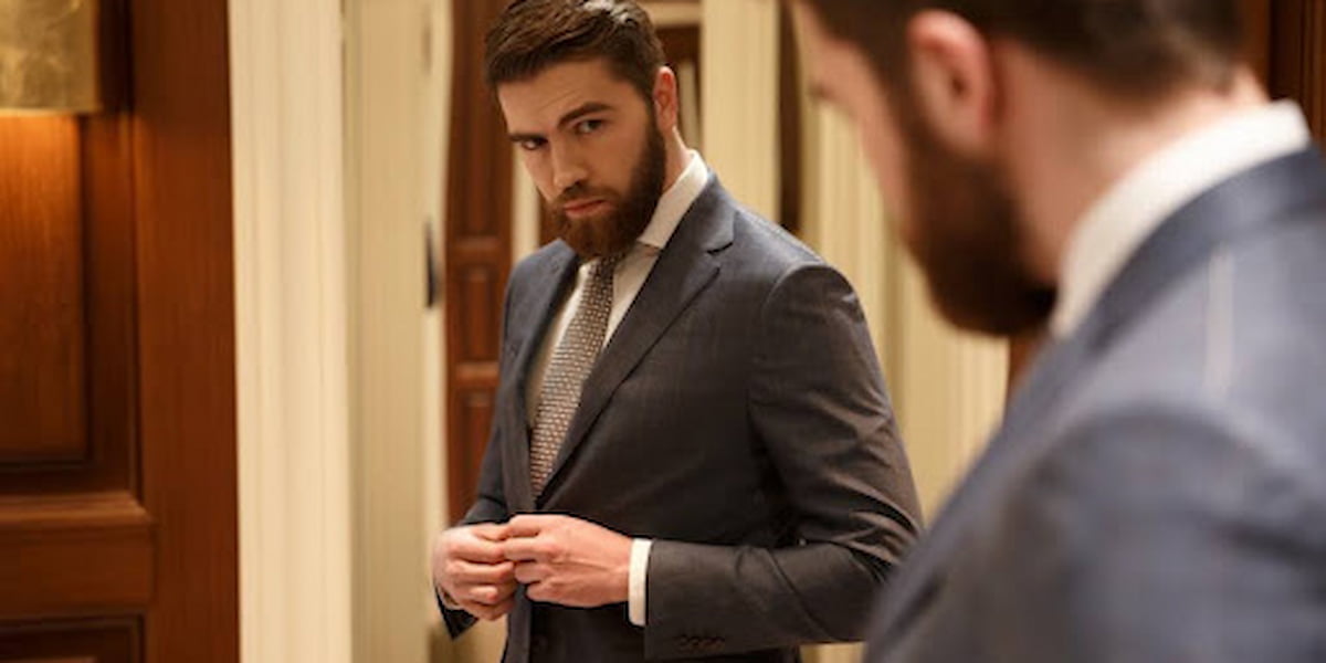 Man adjusting his suit in front of mirror